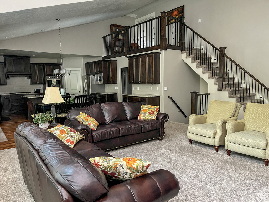Carpeted living room with high vaulted ceiling and stairway