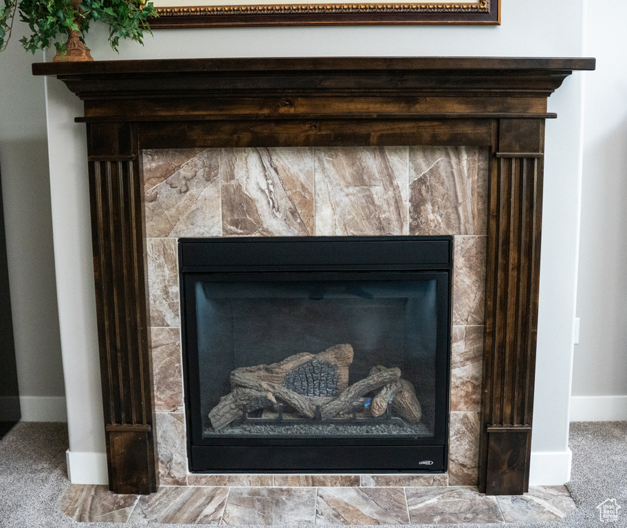 Detailed view of a fireplace, carpet floors, and baseboards
