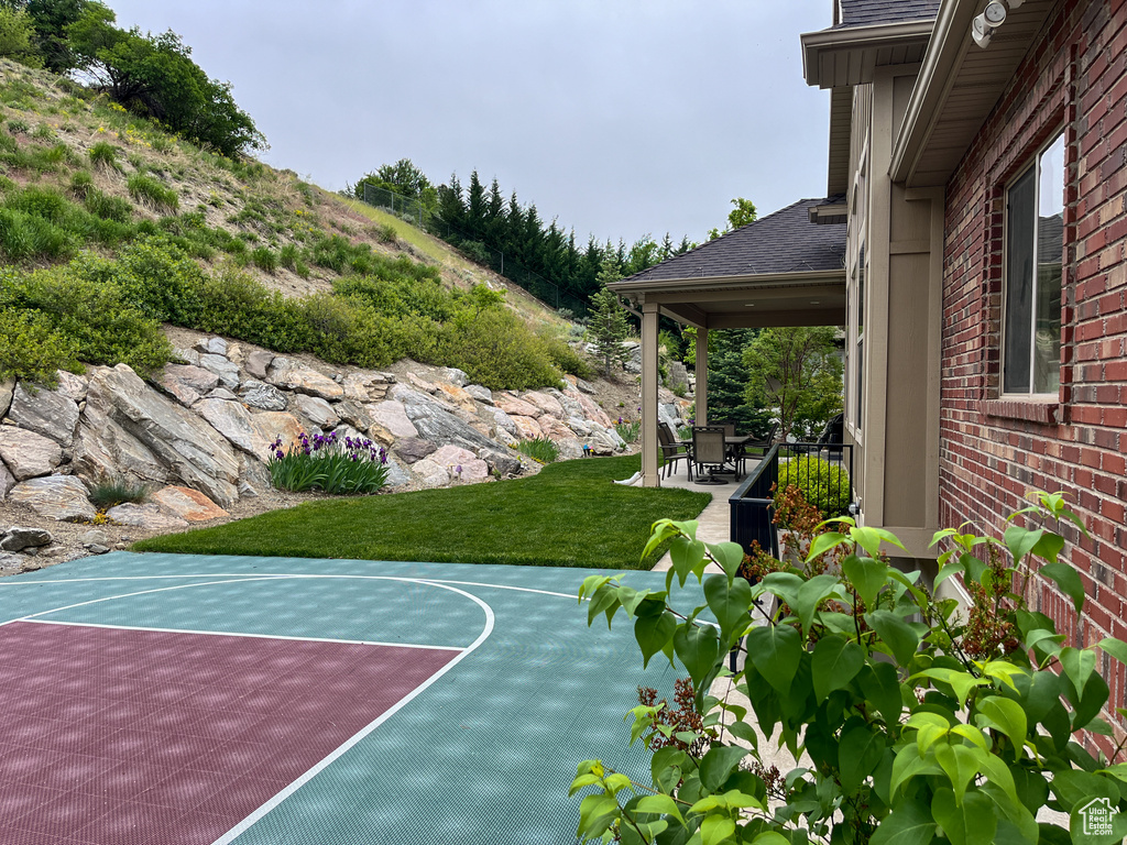 View of basketball court featuring basketball court and a lawn