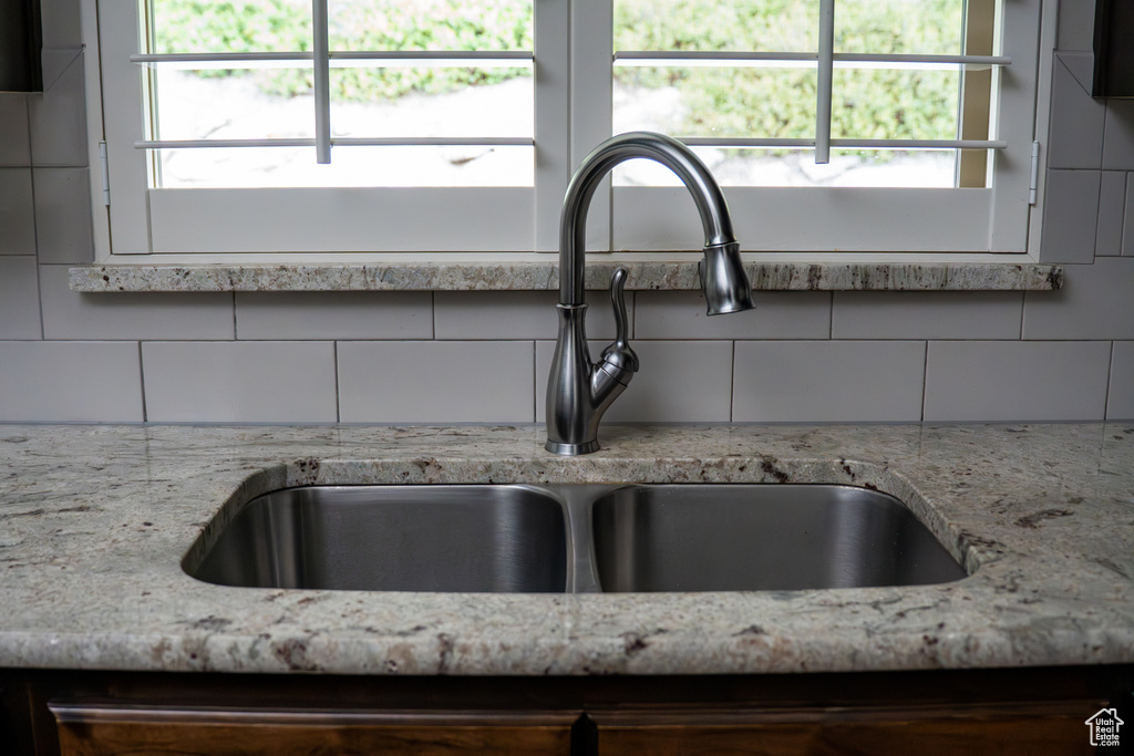 Kitchen view of a sink, tasteful backsplash, and light stone counters