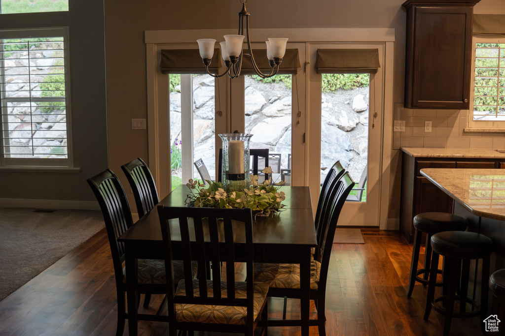 Dining space with a chandelier, dark wood-style floors, and baseboards