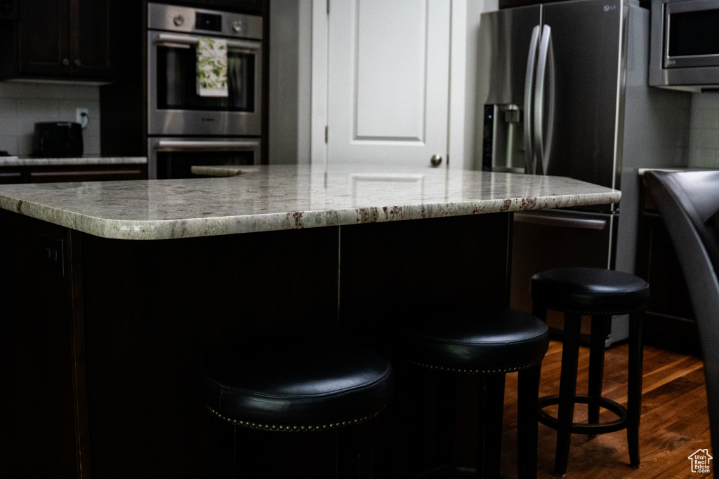 Kitchen featuring appliances with stainless steel finishes, dark wood-style floors, a kitchen island, and dark cabinetry