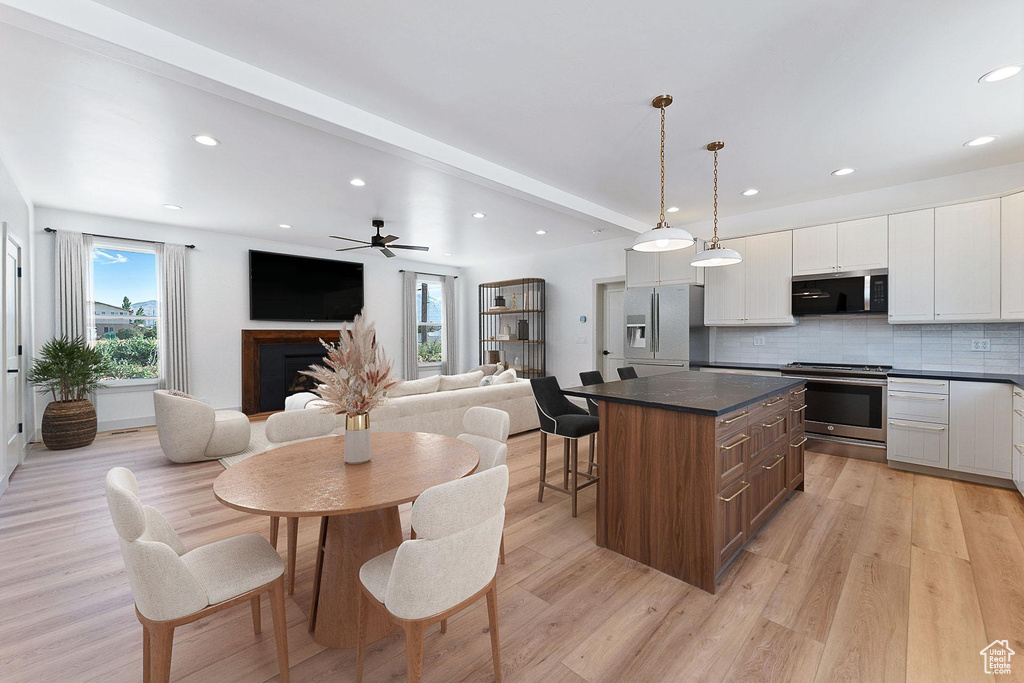 Kitchen featuring appliances with stainless steel finishes, dark countertops, a kitchen island, white cabinets, and decorative backsplash