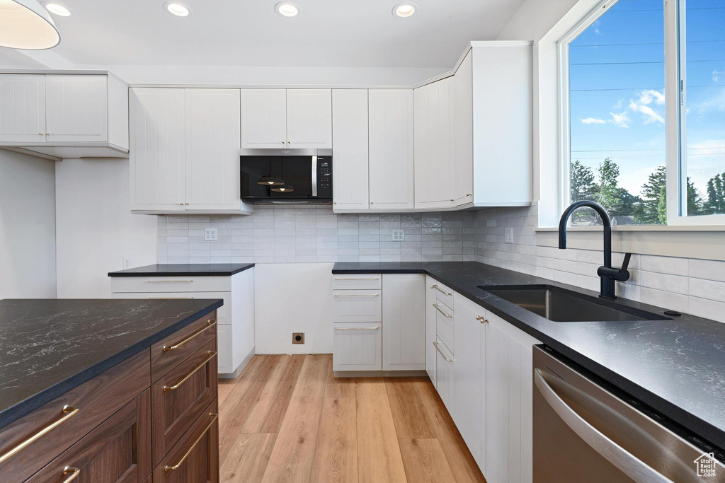 Kitchen with stainless steel appliances, a sink, recessed lighting, light wood-style floors, and backsplash