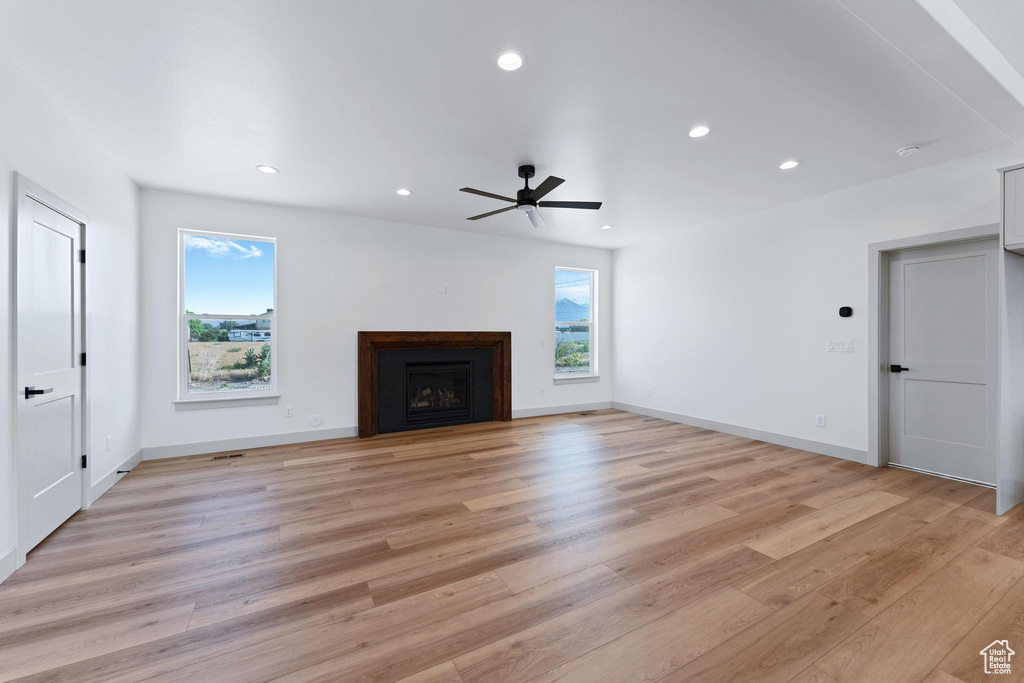 Unfurnished living room featuring light wood-type flooring, recessed lighting, a ceiling fan, a fireplace, and baseboards