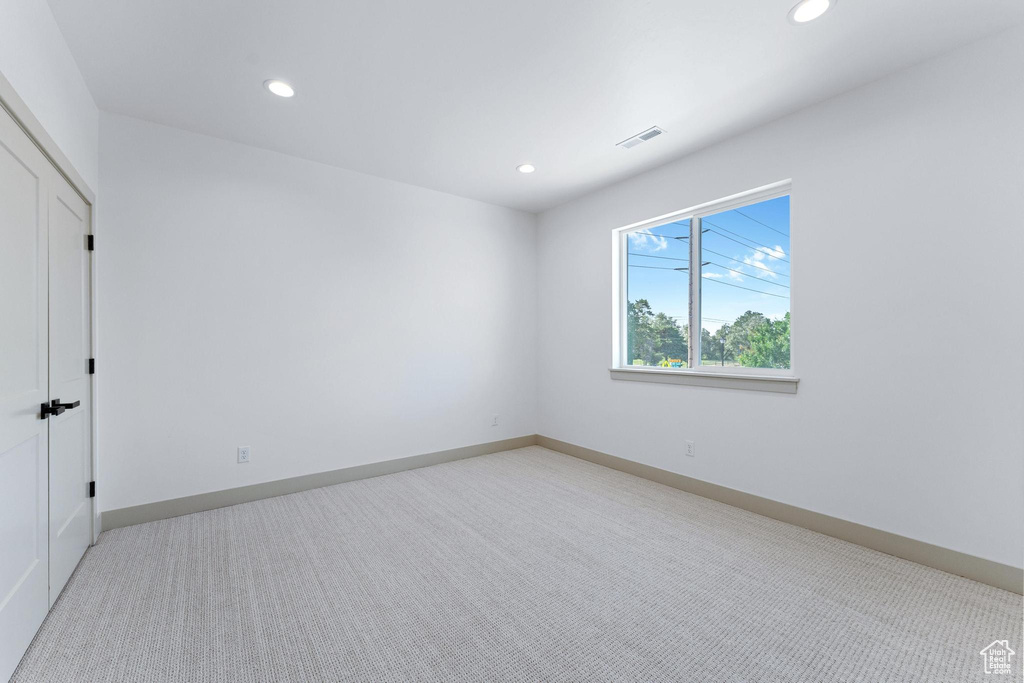 Spare room featuring recessed lighting, light colored carpet, and baseboards