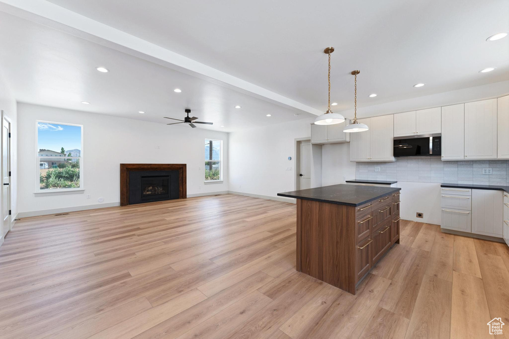 Kitchen with stainless steel microwave, healthy amount of natural light, white cabinetry, recessed lighting, and light wood-style flooring