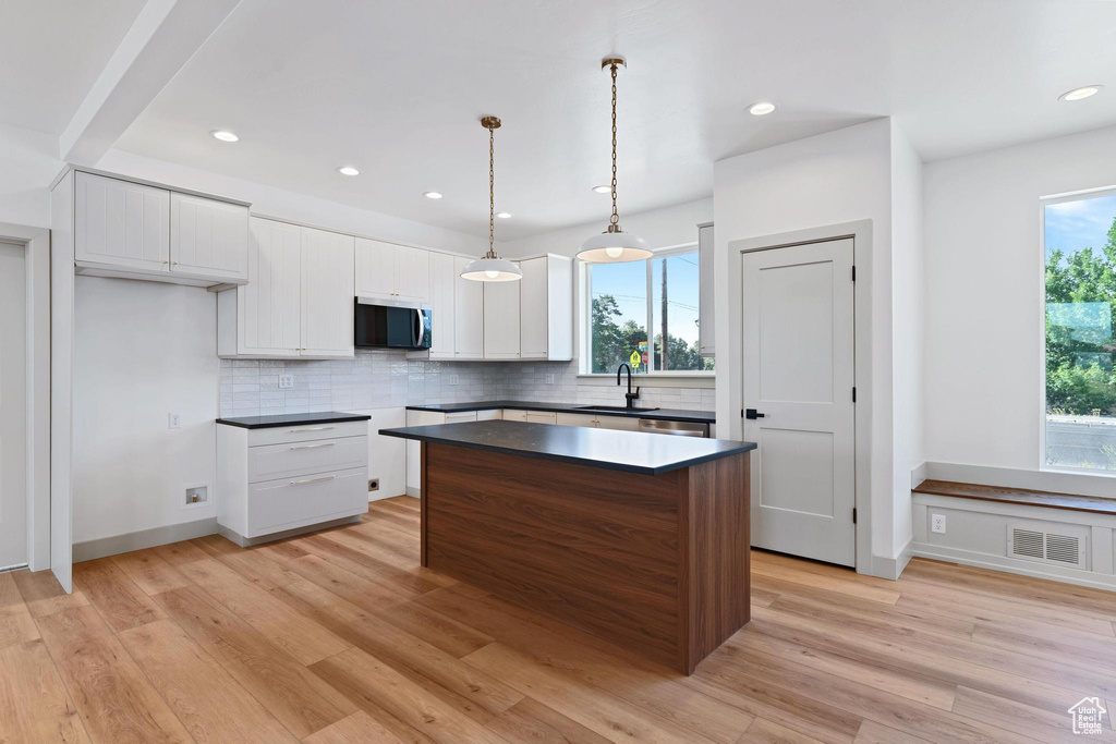 Kitchen with stainless steel microwave, tasteful backsplash, a center island, light wood-type flooring, and recessed lighting
