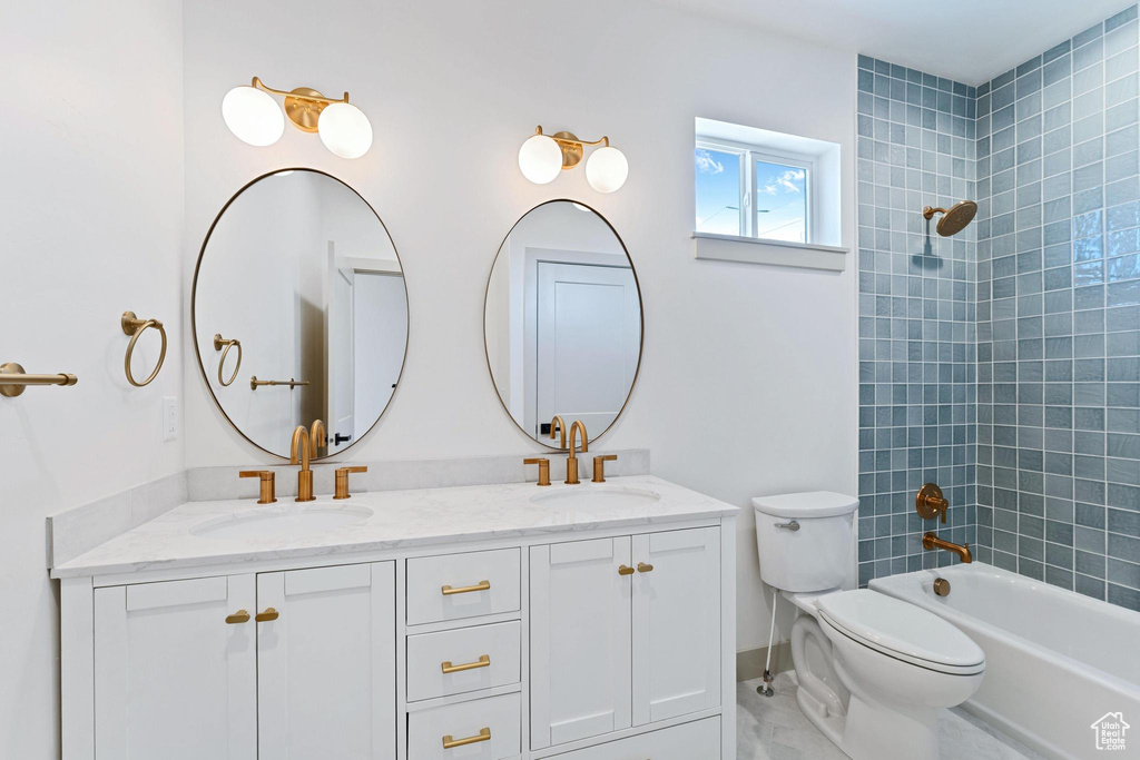 Bathroom featuring double vanity, toilet, washtub / shower combination, marble finish floors, and baseboards