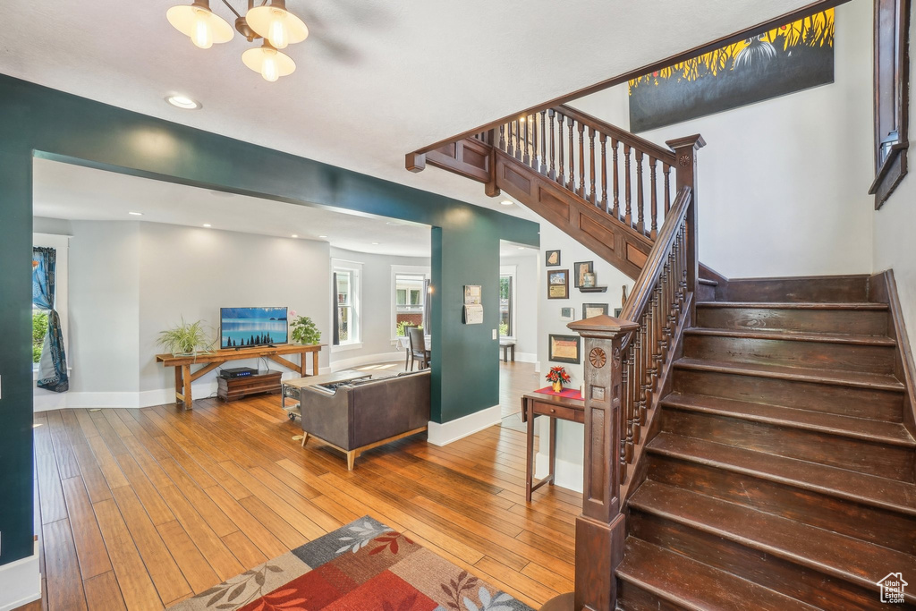 Living room featuring hardwood / wood-style floors, stairs, baseboards, recessed lighting, and a chandelier