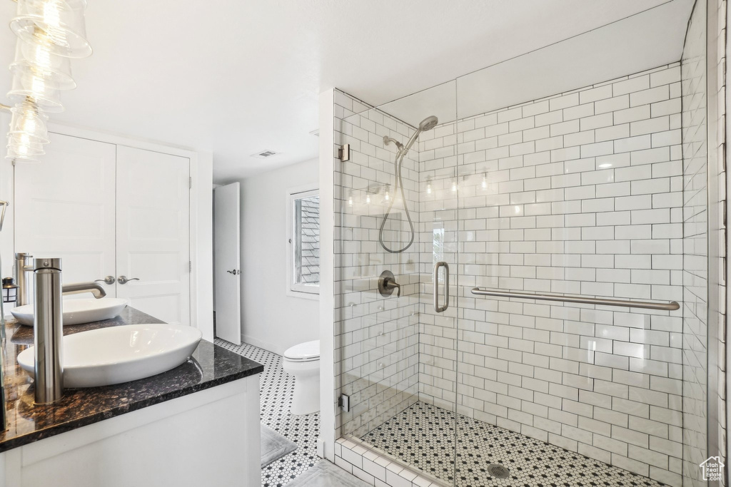 Bathroom with a stall shower, vanity, toilet, tile patterned floors, and baseboards