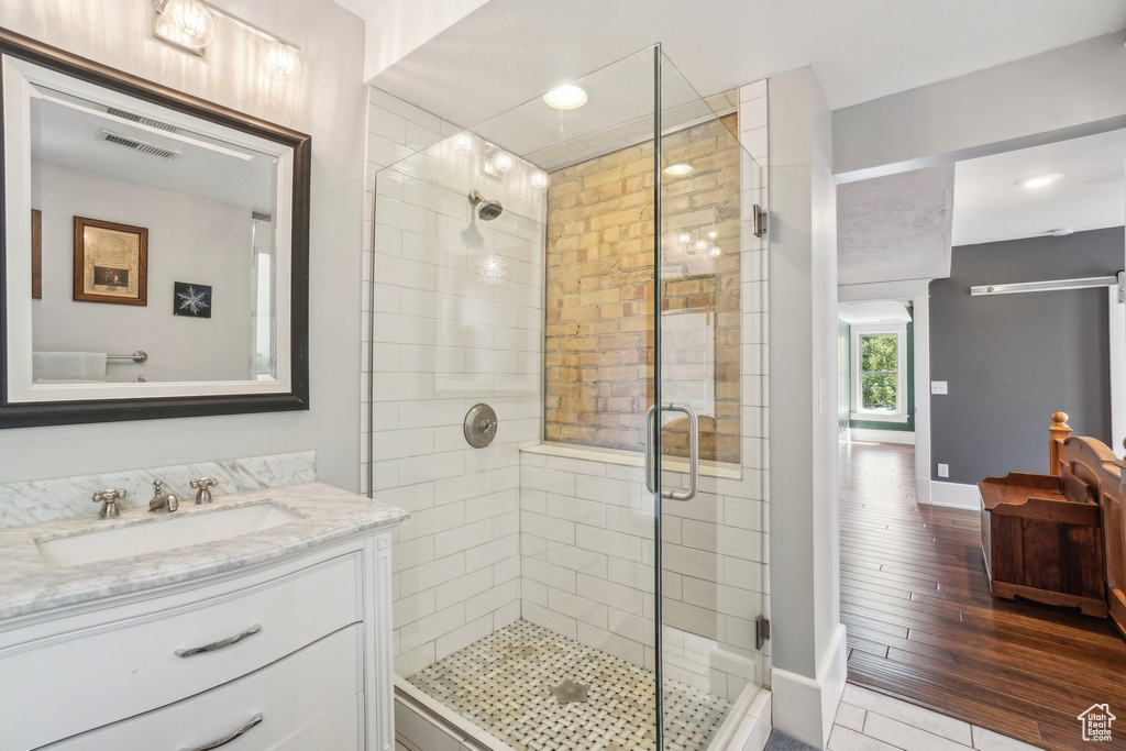 Full bathroom featuring a shower stall, vanity, baseboards, wood finished floors, and recessed lighting