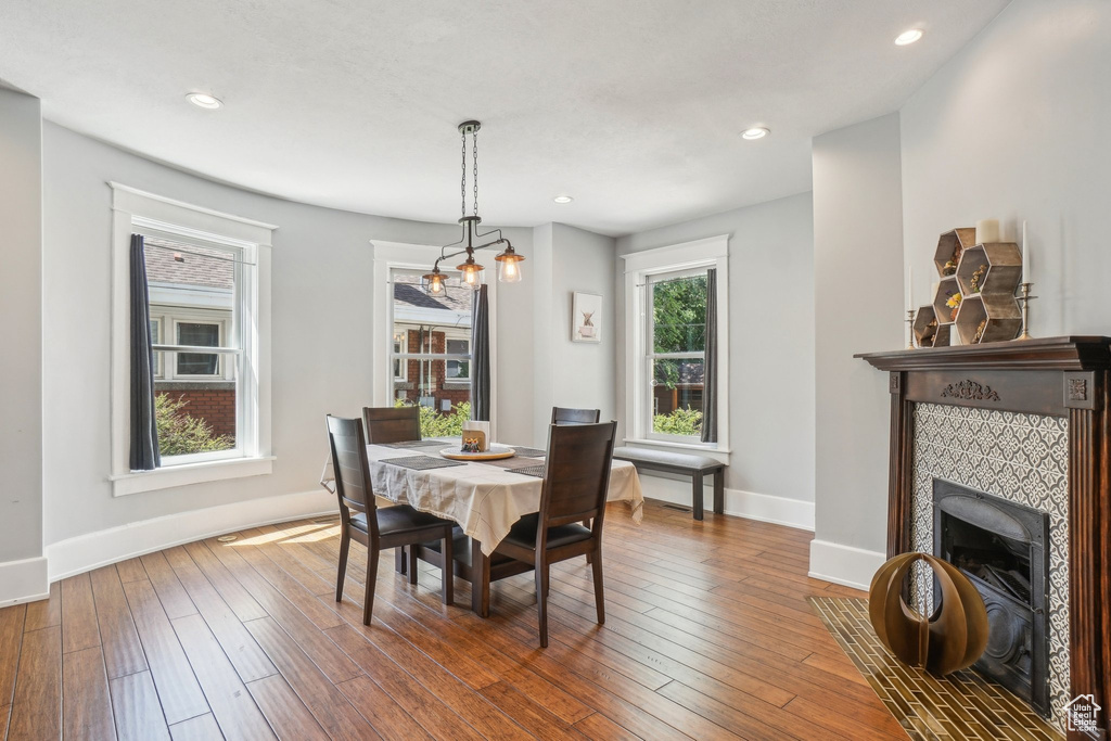 Dining room featuring a fireplace, baseboards, hardwood / wood-style flooring, and recessed lighting