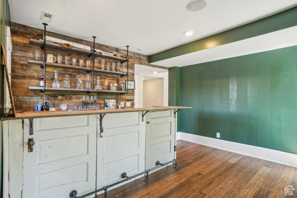Indoor bar featuring baseboards, dark wood-style flooring, and recessed lighting