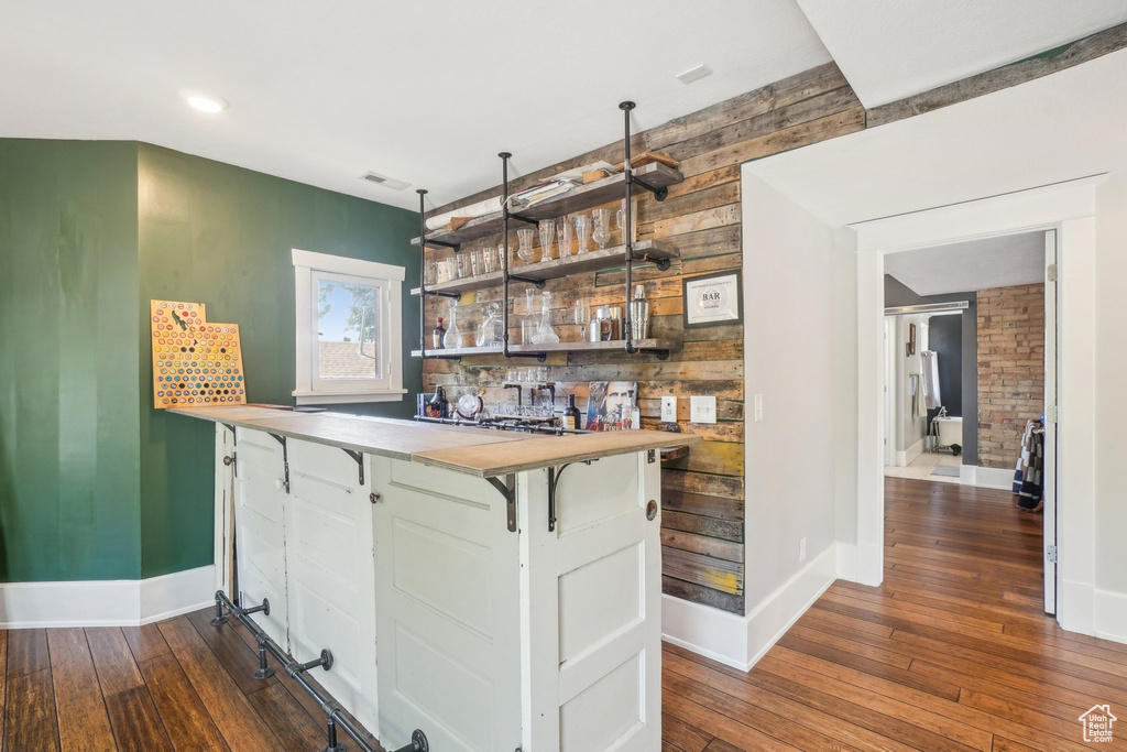 Indoor dry bar featuring dark wood-style floors, baseboards, wood walls, and recessed lighting