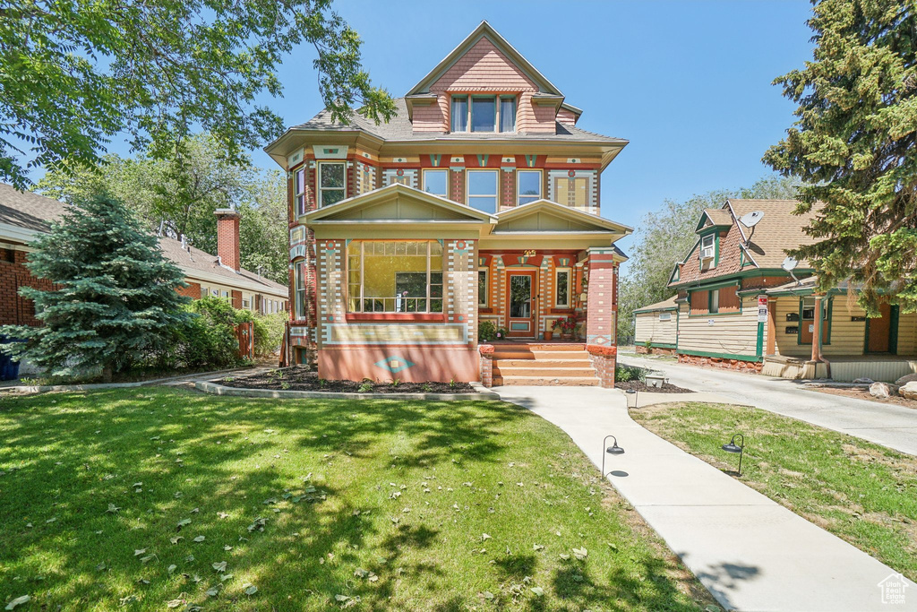 View of front facade featuring a porch, brick siding, and a front lawn