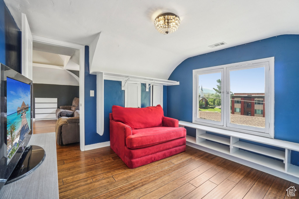 Living area with lofted ceiling and hardwood / wood-style floors