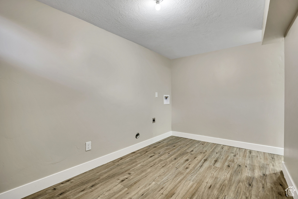 Spare room with baseboards, wood finished floors, and a textured ceiling