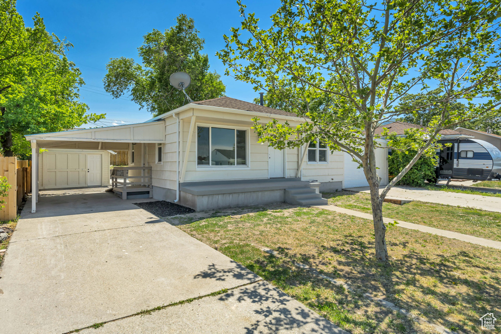 View of front facade featuring driveway, an attached carport, and a porch