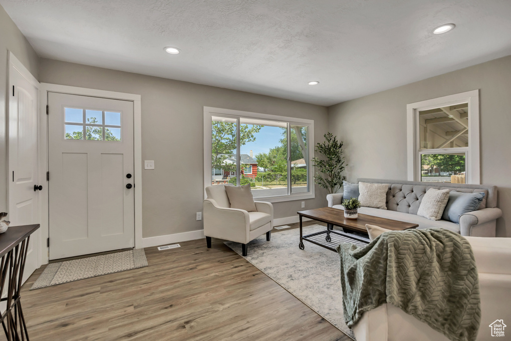Living room with plenty of natural light, baseboards, recessed lighting, and light wood-style floors