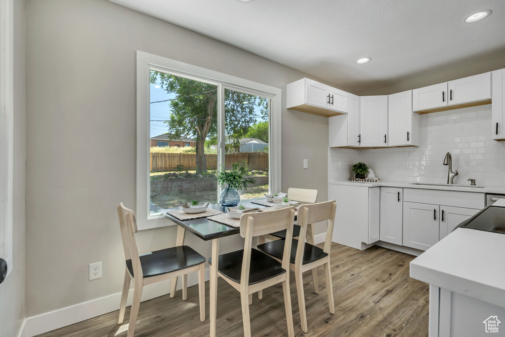 Kitchen featuring a sink, backsplash, light wood-style floors, white cabinetry, and recessed lighting