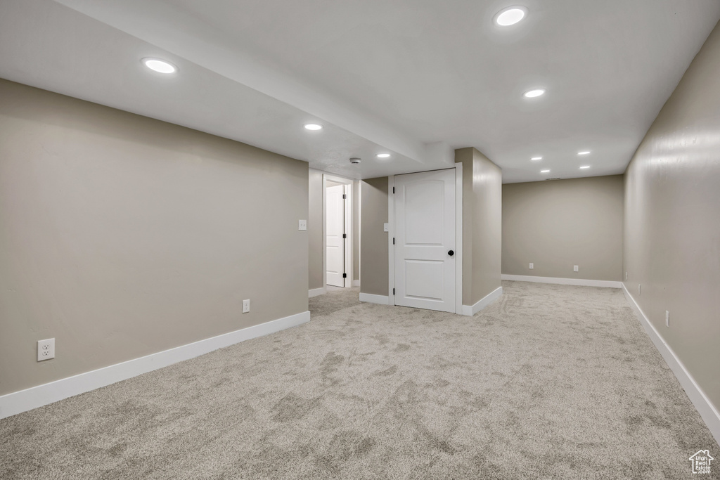 Finished below grade area featuring light colored carpet, recessed lighting, and baseboards