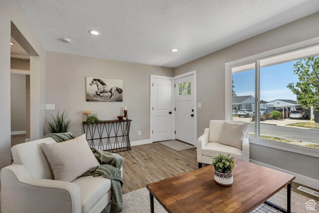 Living area with baseboards, light wood-style flooring, and recessed lighting