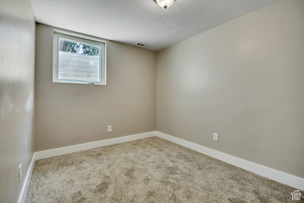 Unfurnished room featuring carpet flooring, baseboards, and a textured ceiling