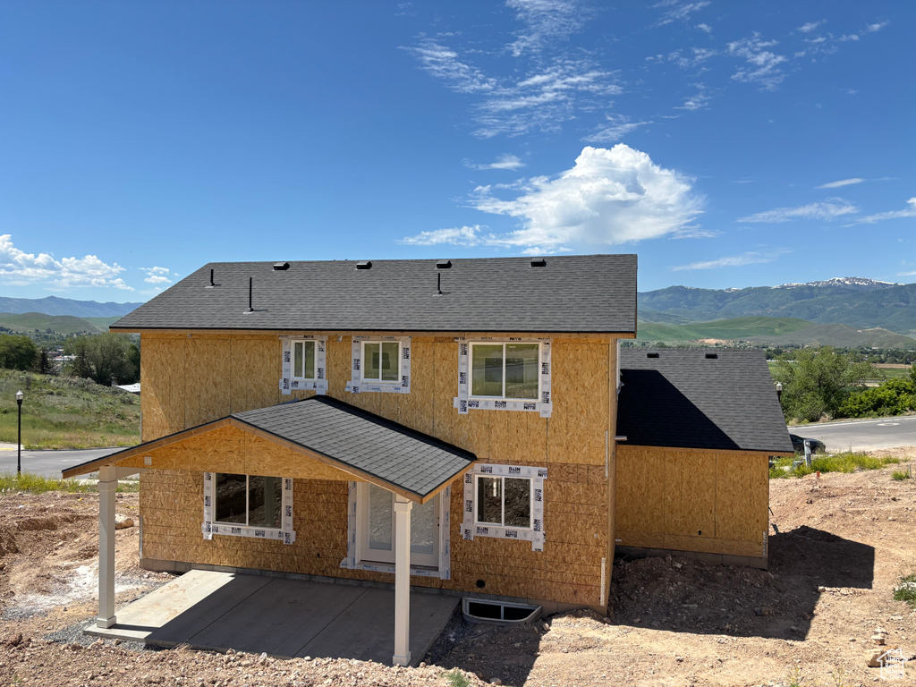 Back of house with a mountain view and a shingled roof