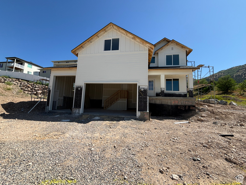 Back of property with board and batten siding, stairway, and a garage