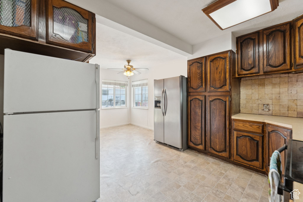 Kitchen featuring freestanding refrigerator, stainless steel refrigerator with ice dispenser, light countertops, backsplash, and a ceiling fan
