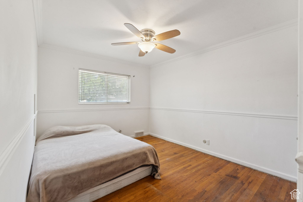 Bedroom featuring wood finished floors, ornamental molding, baseboards, and ceiling fan