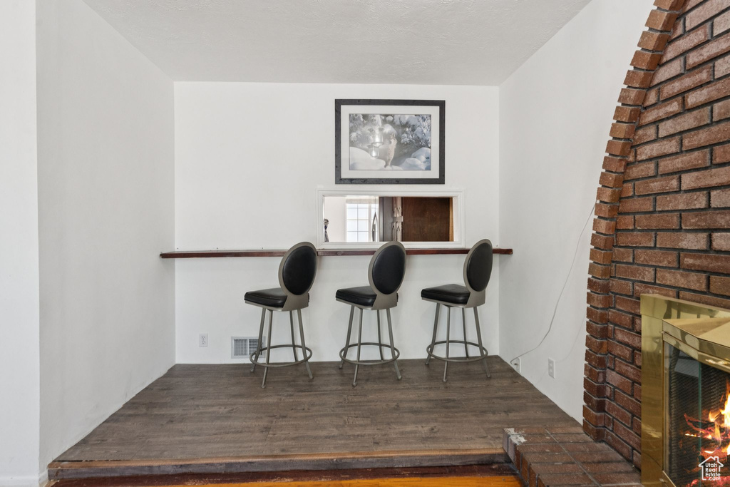 Indoor dry bar with a brick fireplace and wood finished floors