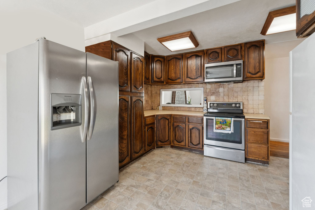 Kitchen with appliances with stainless steel finishes, light countertops, and backsplash