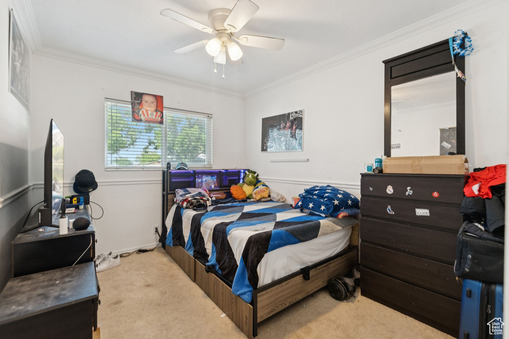 Carpeted bedroom featuring ornamental molding and ceiling fan