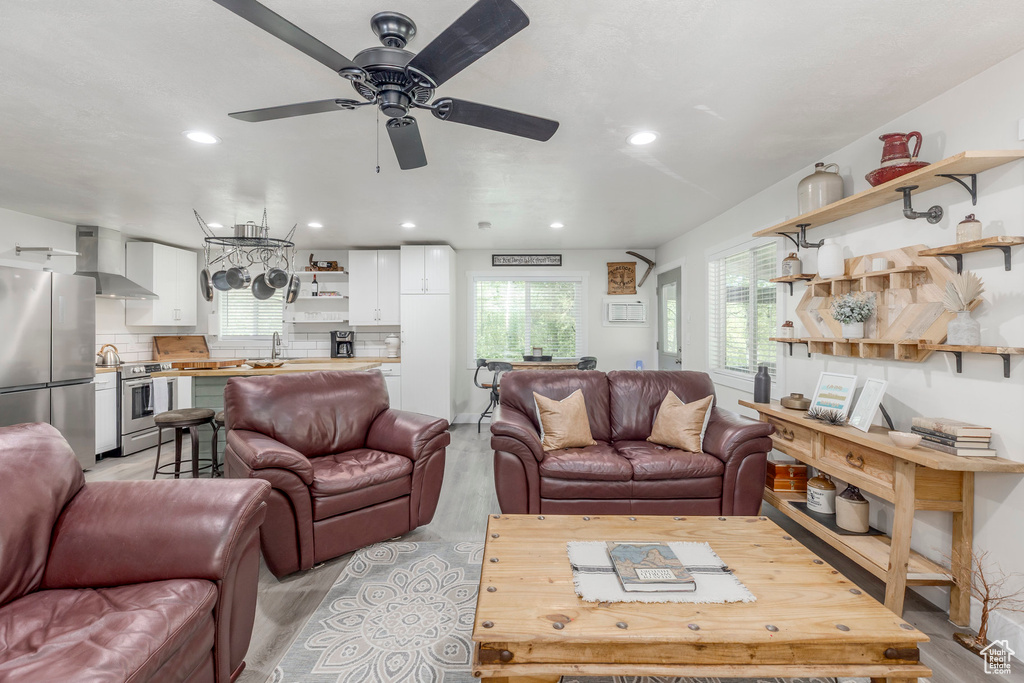 Living room with light wood-type flooring, a ceiling fan, and recessed lighting