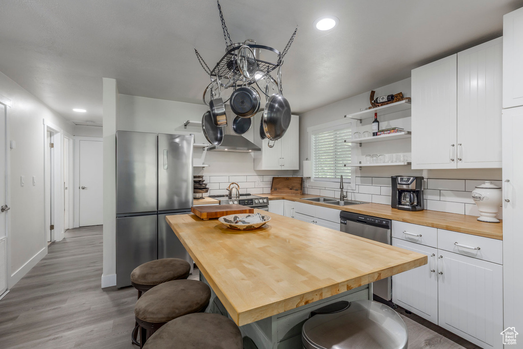 Kitchen featuring butcher block countertops, appliances with stainless steel finishes, open shelves, a sink, and recessed lighting