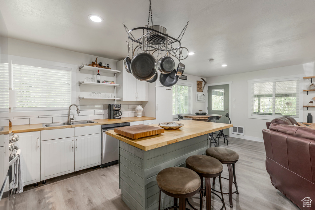 Kitchen with wood counters, a sink, appliances with stainless steel finishes, open floor plan, and a kitchen breakfast bar