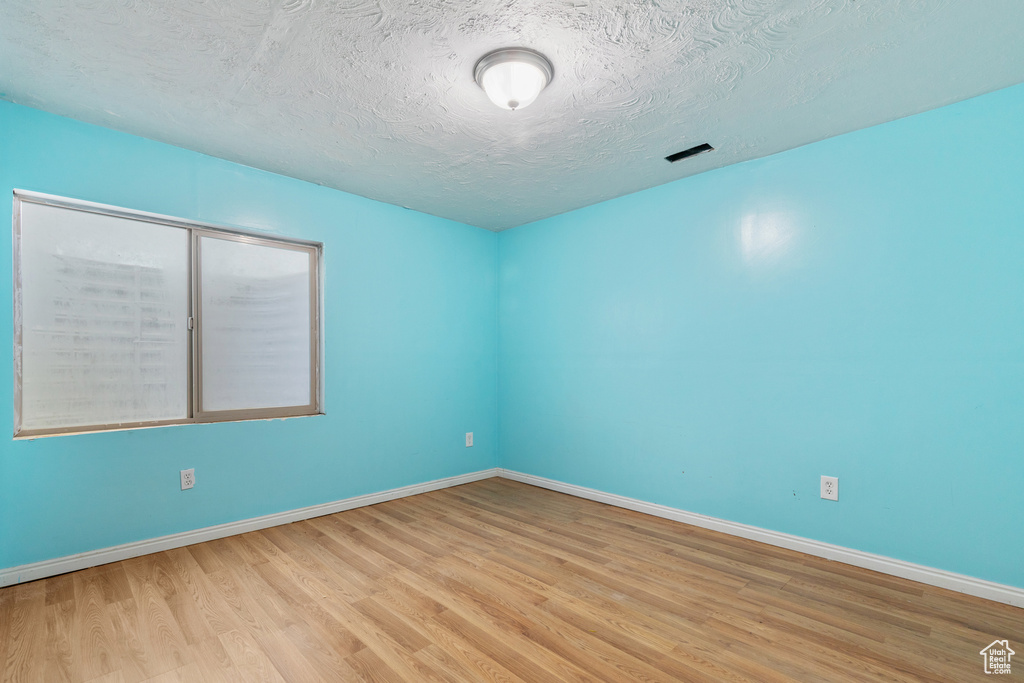 Spare room featuring wood finished floors, baseboards, and a textured ceiling