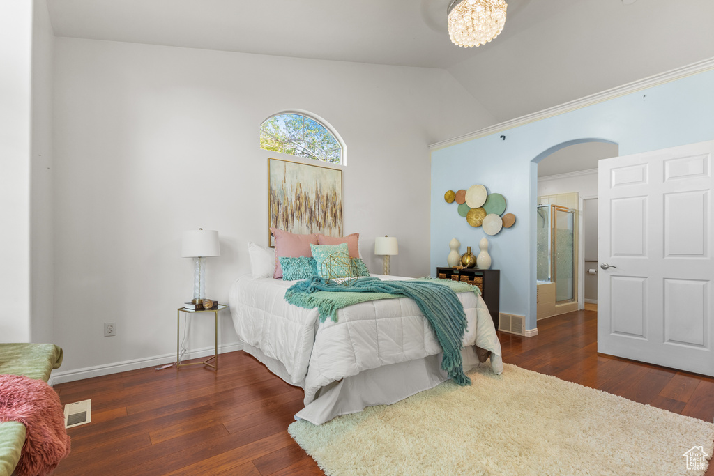 Bedroom featuring arched walkways, wood finished floors, lofted ceiling, baseboards, and a chandelier