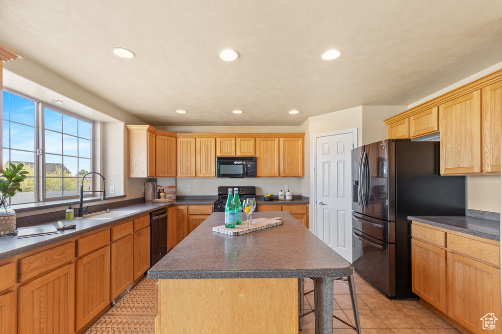 Kitchen with range, black microwave, refrigerator with ice dispenser, dark countertops, and a breakfast bar area