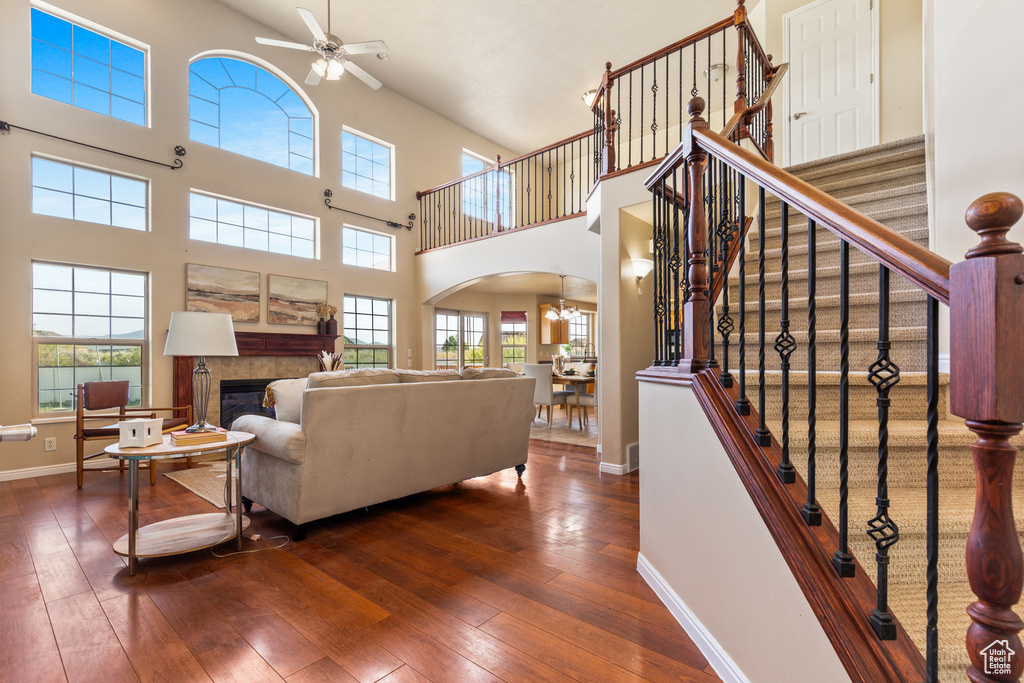 Living area featuring arched walkways, a ceiling fan, a high ceiling, dark wood finished floors, and baseboards