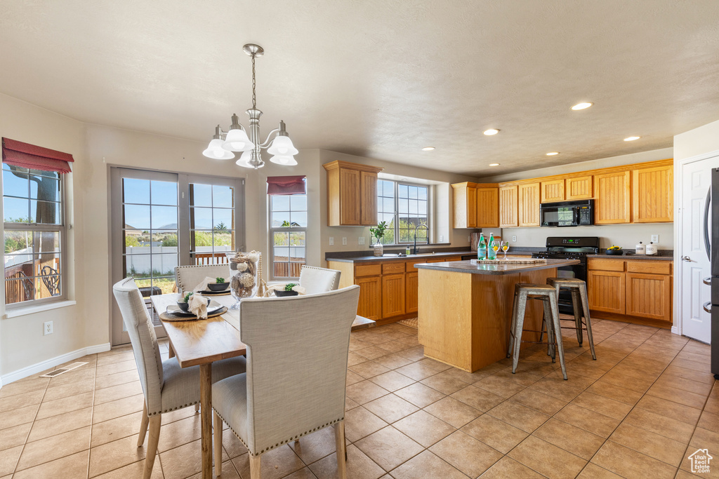 Kitchen with black microwave, a center island, a chandelier, a breakfast bar area, and recessed lighting