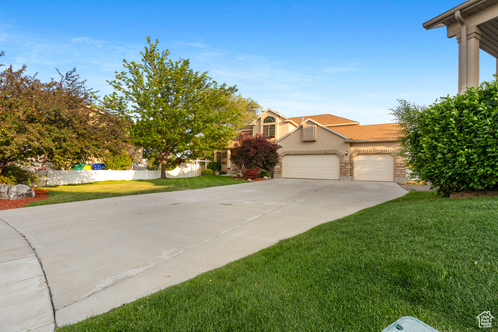 View of front of home with stucco siding, driveway, a front lawn, and a garage
