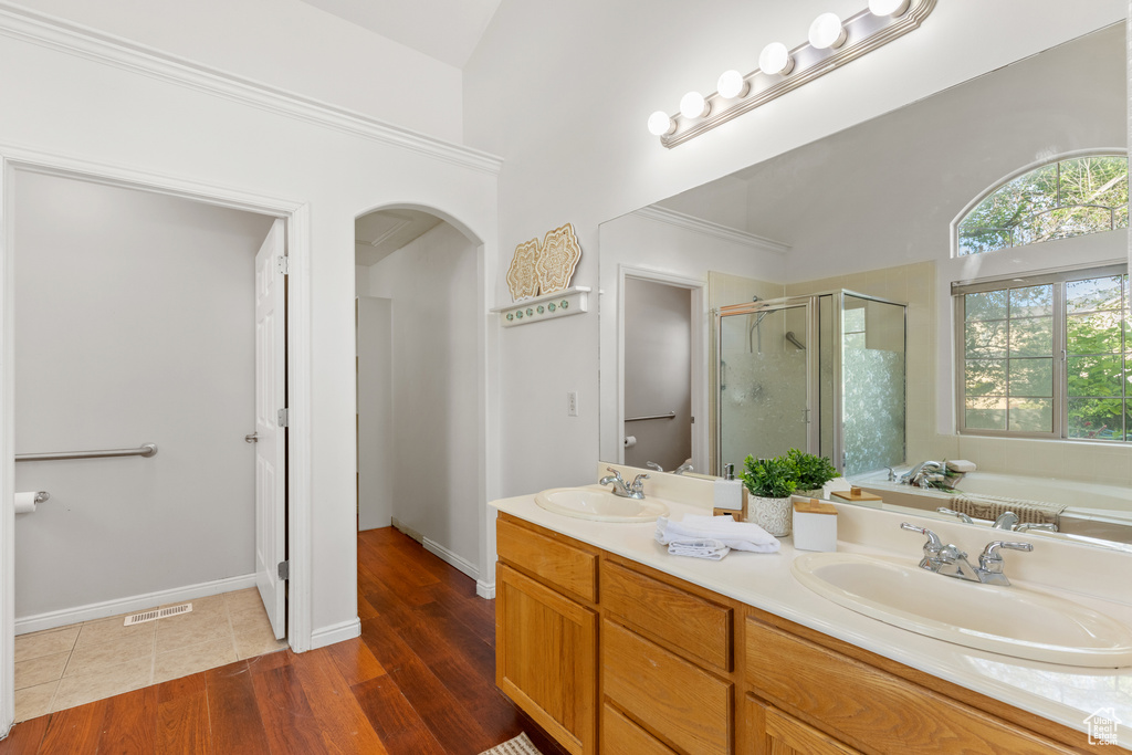Full bathroom featuring a stall shower, a garden tub, double vanity, and wood finished floors