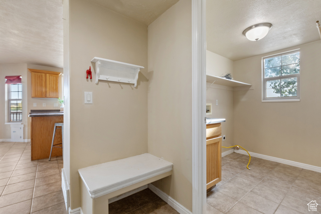 Mudroom featuring light tile patterned flooring, healthy amount of natural light, and baseboards