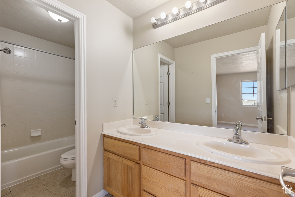 Full bathroom featuring double vanity, tile patterned flooring, toilet, and shower / bath combination