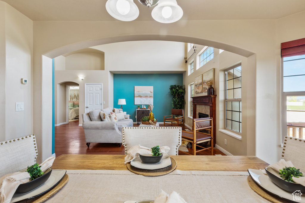 Living area featuring arched walkways, wood finished floors, a fireplace, a chandelier, and baseboards