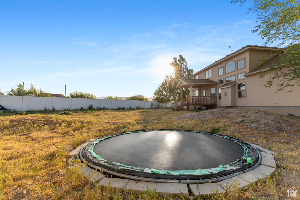 View of yard featuring a trampoline and a deck