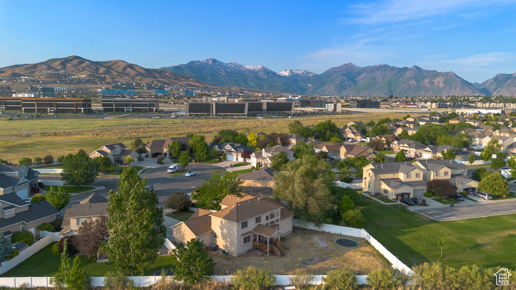 Aerial view of property and surrounding area featuring mountains and nearby suburban area